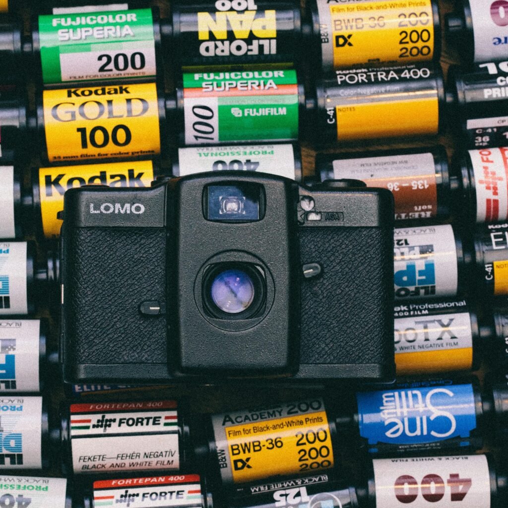 Flat lay of a vintage camera surrounded by various film rolls, showcasing analog photography.